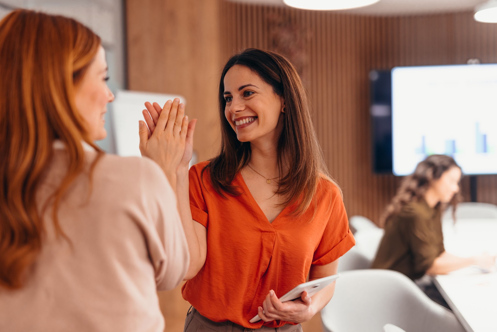 Two businesswomen high-fiving celebrating success in the office